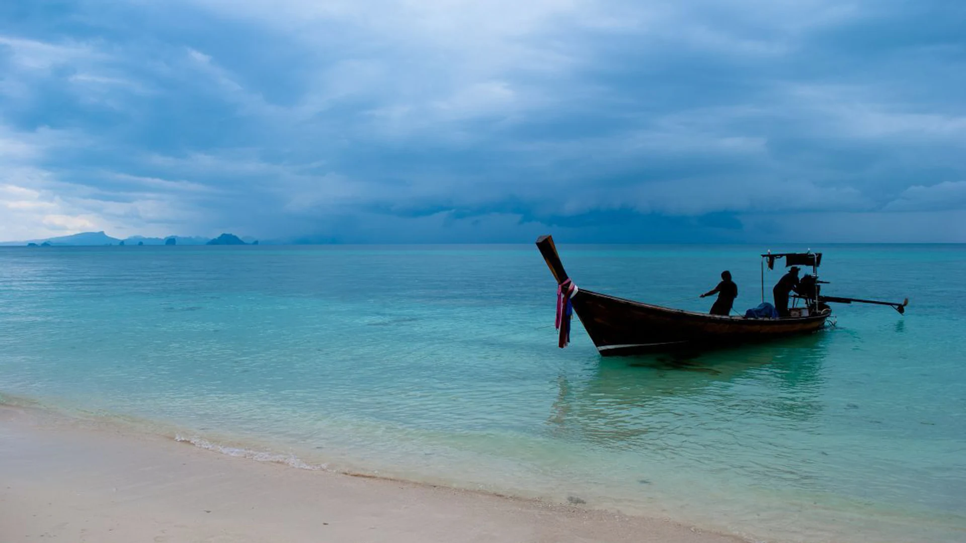 Longtail boat in turquoise shallows off a white-sand beach on Ko Hae (Coral Island), Phuket